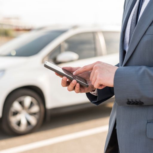 Hombre con Smartphone enfrente de coche Hombre con Smartphone enfrente de coche